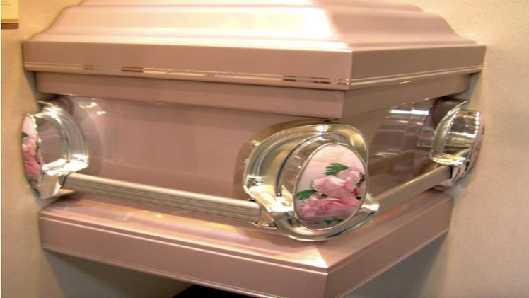 closeup of a casket display featuring pink roses imbedded in a silver casket corner